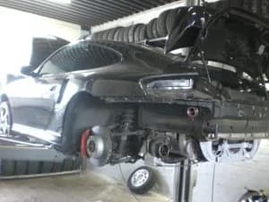 Fahrzeug auf der Hebebühne mit abmontiertem Vorderrad in der Werkstatt von Auto-Stadt